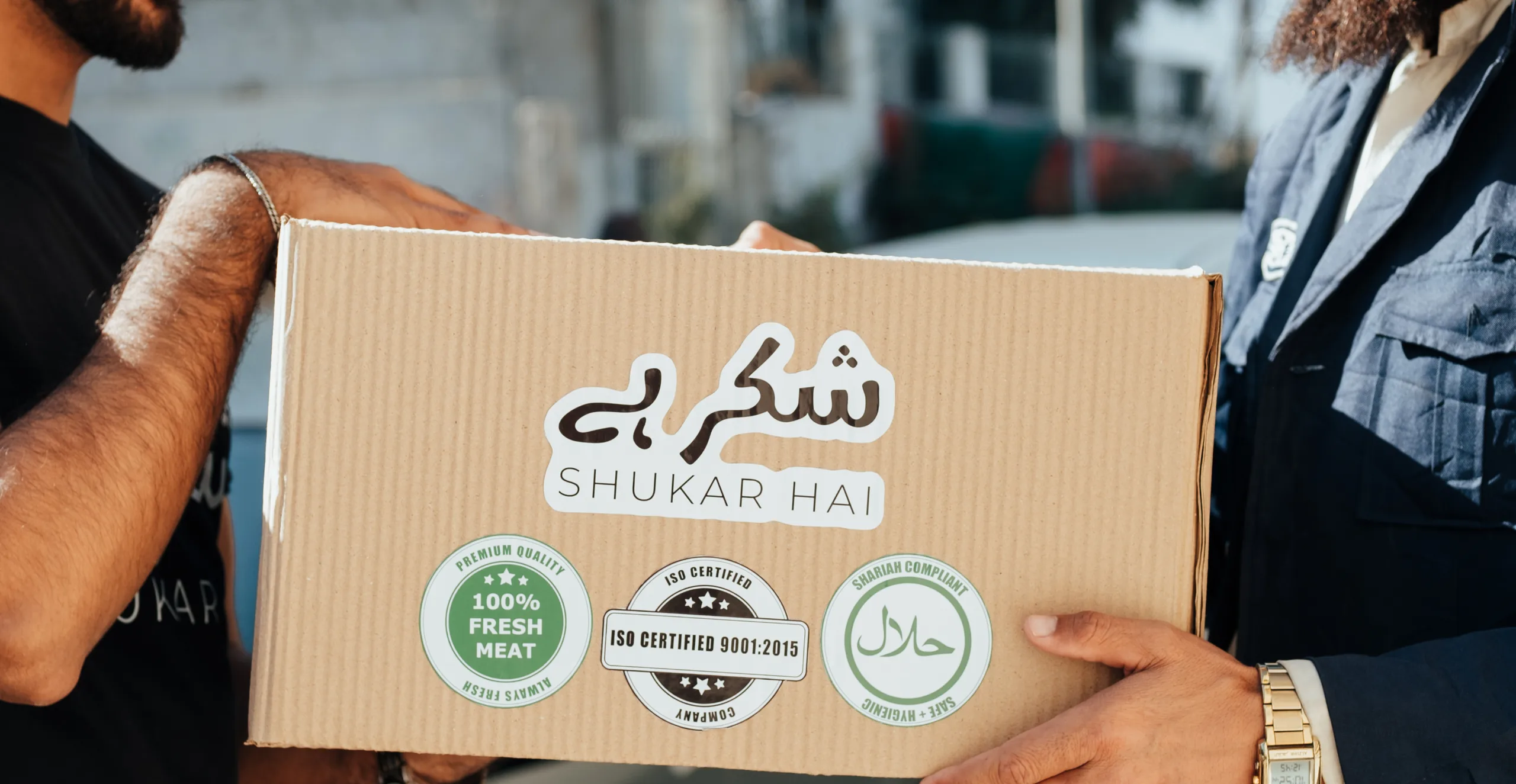 A certified Shukar Hai meat box with fresh, ISO, and halal seals being handed over